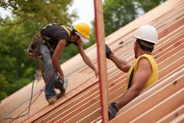Hispanic carpenters placing roof panel at a house under construction