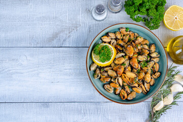 Delicious seafood mussels with lemon and parsley. Space for text or logo. Wooden table. Top view - obrazy, fototapety, plakaty