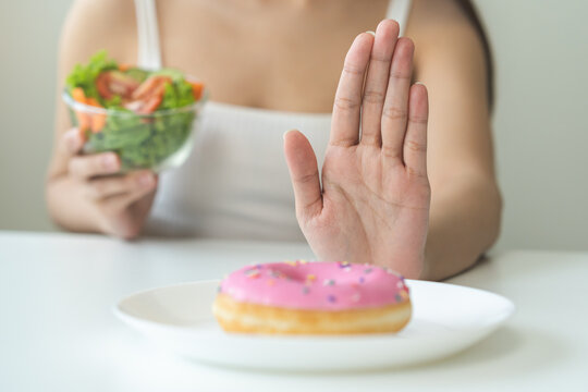 Diet, Dieting Asian Young Woman, Girl Hand Push Out, Deny Sweet Donut On Plate, Dish And Choose To Eat Green Salad Vegetables In Bowl On Table, Food Good Healthy, Health Person, Female Weight Loss.