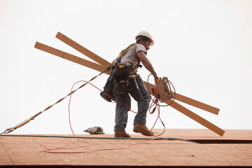 Carpenter carrying boards and a circular saw at a construction site