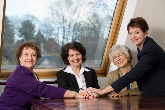 Portrait of smiling business women sitting by a table.