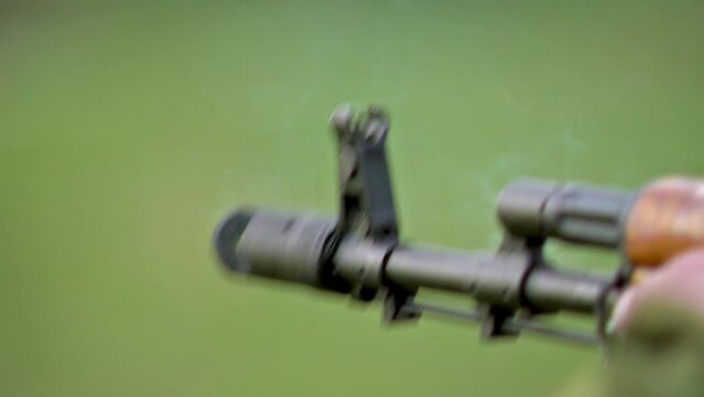 Shooting from a Kalashnikov Assault Rifle.Several Shots from Barrel. Closeup outdoor Shot. Shooting Smoke. Blurred Background.
