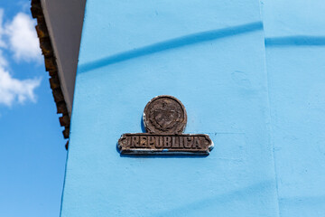 Republic sign (Republica in Spanish) and the Cuban coat of arms on a blue wall of an old building in Cuba, North America