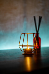 Close-up of a cozy candle inside a metal holder on a wooden table
