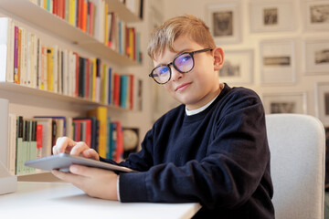 ritratto di studente che seduto di fronte alla sua scrivania utilizza il suo tablet