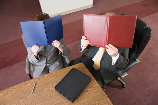 View from above of business people covering their faces with files.