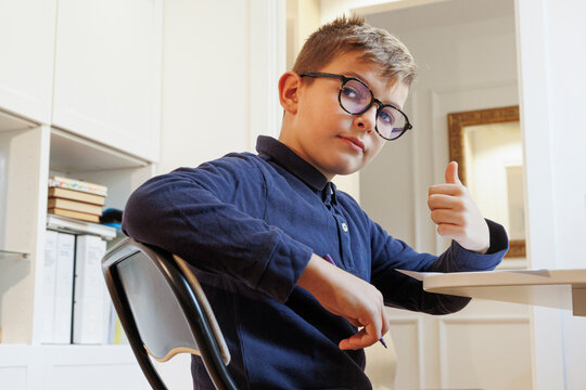 ritratto di studente che fa il segno dell' ok seduto di fronte alla sua scrivania