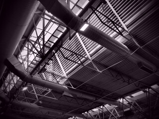 The roof of a hangar, a production hall or a sports hall. Metal structures, beams, supporting elements. Ventilation systems in large halls and rooms. Skylights. Industrial interior.
