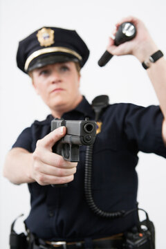 Police woman pointing handgun and holding flashlight.