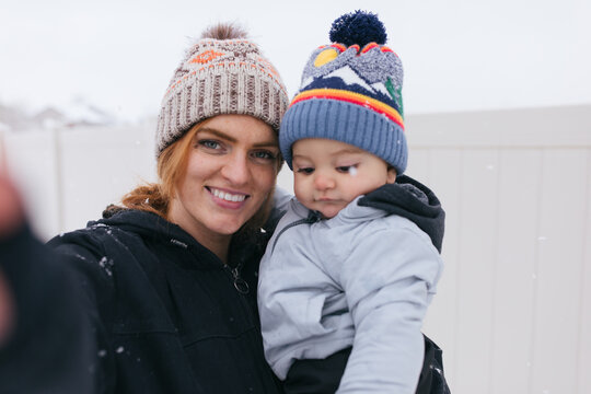 Redhead mom and baby taking selfie outside in the snowfall 
