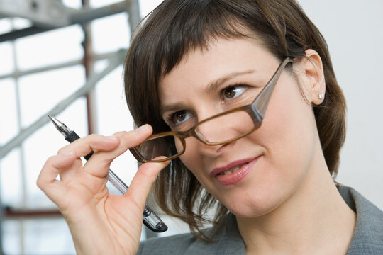 Close-up of a businesswoman holding eyeglasses and smirking