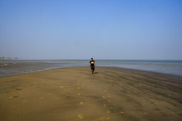 south asian young boy walking alone on the beach