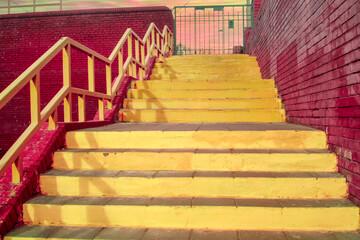 The yellow staircase and brick walls of the trend color vivid magenta. Ascent to the sunset sky. Geometry in architecture. Bright colors. Space for text.