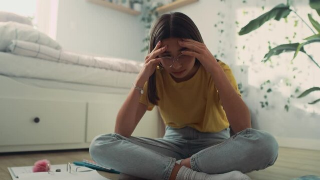 Overwhelmed caucasian teenage girl sitting on bed with head in hands and trying to learn. Shot with RED helium camera in 8K.   
