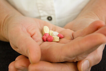 Senior woman holds many different pills in her hands close up