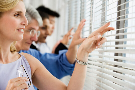 View of business executives peeping through blinds.