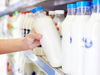 Woman chooses milk and dairy products at store