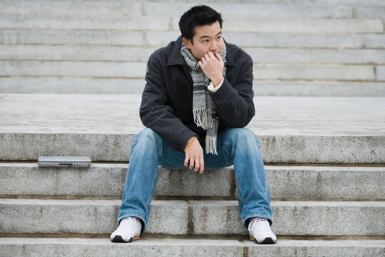 Young man waiting on steps with a laptop