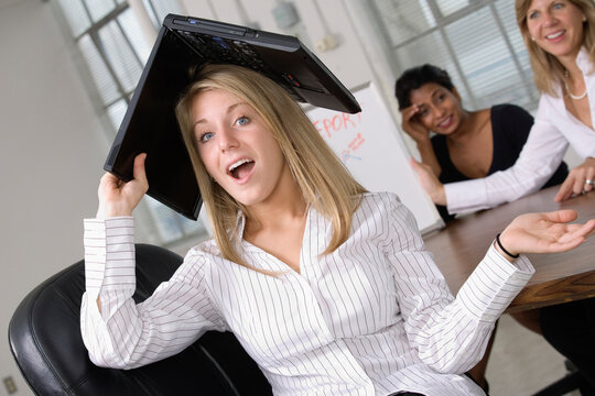 Portrait of a business woman with a laptop over her head.