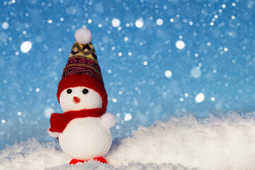 The snowman is standing in the snow and it is snowing. Festive Christmas card.