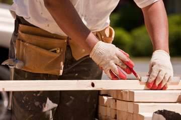 Carpenter measuring wall studs at a construction site