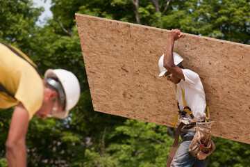Carpenters carrying a particle board