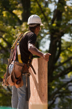 Carpenter carrying a particle board at a construction site