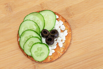 Crispy Cracker Sandwich with Fresh Cucumber, Cottage Cheese and Olives on Cutting Board. Diet Food....