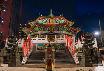 This image shows an ornate temple entrance in a Japanese Chinatown at night.