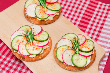 Light Breakfast or Diet Eating - Crispy Cracker Sandwich with Cream Cheese, Fresh Cucumber and Radish on Wooden Cooking Board on Magenta Background