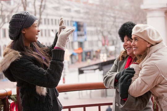 A woman taking a picture of two friends outside during the Christmas season; Boston, Massachusetts, United States of America