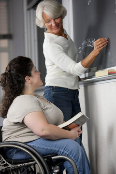 Female professor and a student with Spina Bifida in classroom