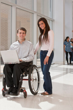 Teacher with spinal cord injury in wheelchair with their students in the background