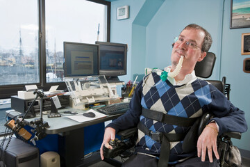 Businessman with Duchenne muscular dystrophy using a breathing ventilator in an office
