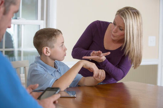 Mother communicating with son in American Sign Language 'School' at home