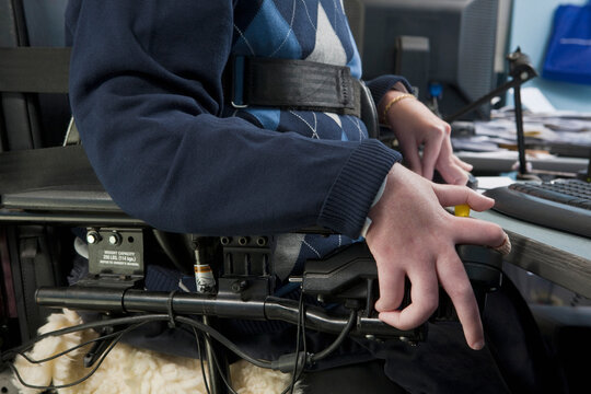 Businessman with Duchenne muscular dystrophy in a motorized wheelchair working in an office