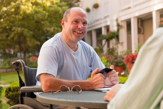 Businessman with Friedreich's Ataxia text messaging on a mobile phone with hand degeneration