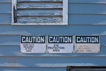 Warning sign saying 'Hardhat and Eye Protection Required In This Area' at manufacturing plant
