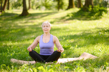 Athletic middle-aged woman doing yoga outdoors in a city park.Meditation concept