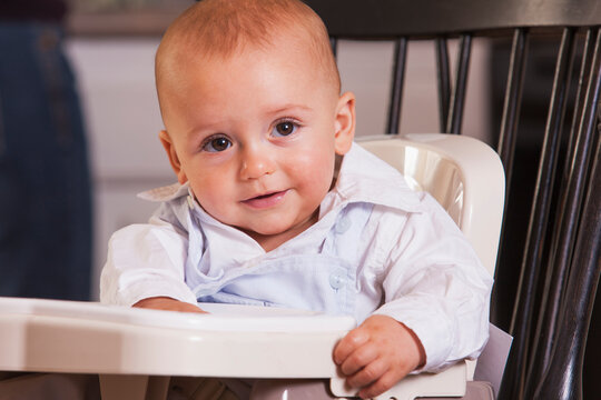 Smiling baby boy sitting in a booster seat