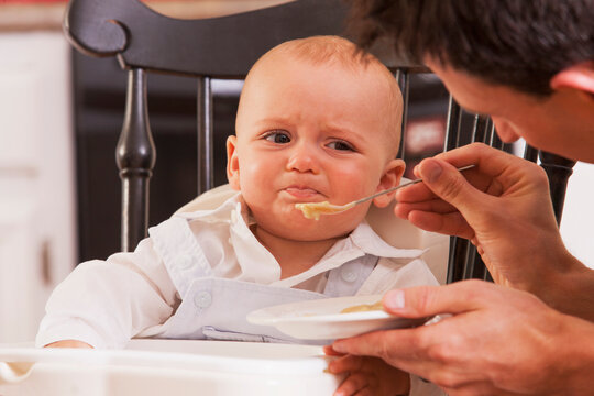 Father feeding food to his son who is refusing to eat
