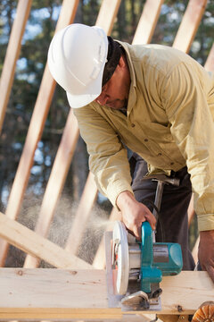 Carpenter using a circular saw on stud