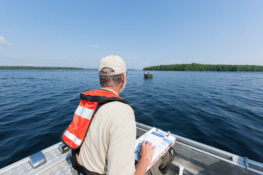Public works engineer on service boat preparing to take public water samples from reservoir