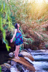 latin mid adult woman standing on a stone eyes closed meditating or enjoying present moment in the Cochiguaz river in the Valle del Elqui	