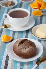 Fresh bun with butter and tea, orange for breakfast