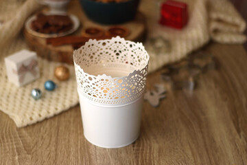 Various Christmas decorations, cup of tea or coffee, sweets, small presents, knitted blanket and candles. Selective focus.