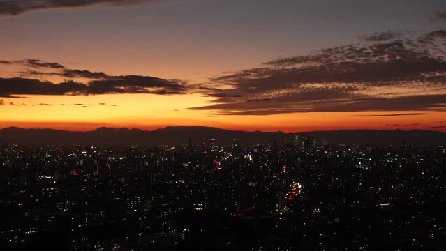 NAGOYA, JAPAN - OCT 2022 : Aerial high angle view of NAGOYA CITY in sunset. View of buildings and street traffic around Nagoya station and Sakae area (central downtown). Time lapse shot, dusk to night
