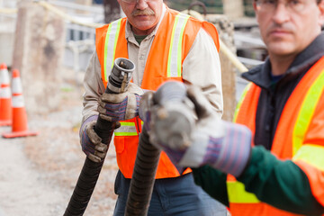 Environmental engineers examining hose coupling for toxic waste petroleum cleanup