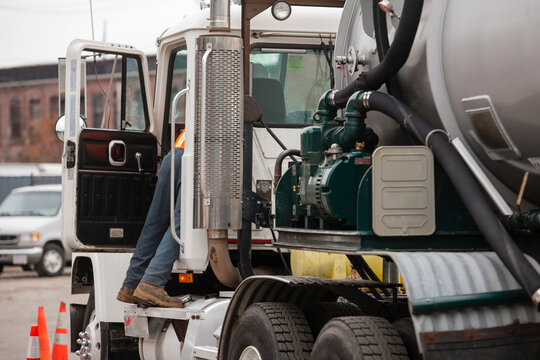 Environmental engineer reaching in driver's side of tanker truck for hazardous waste cleanup