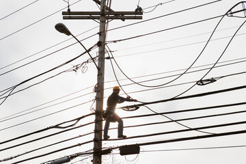 Communications worker on a power pole installing new cable to existing bundles